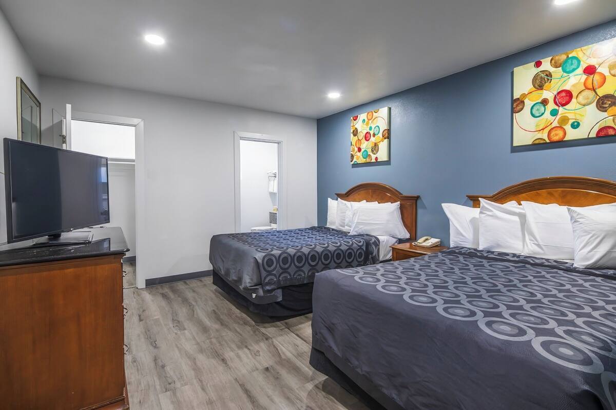 A hotel room with two beds, a TV, and artwork on the walls.