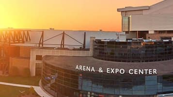 The exterior of the Arena & Expo Center with a modern architectural design, featuring a curved glass facade and a prominent entrance.