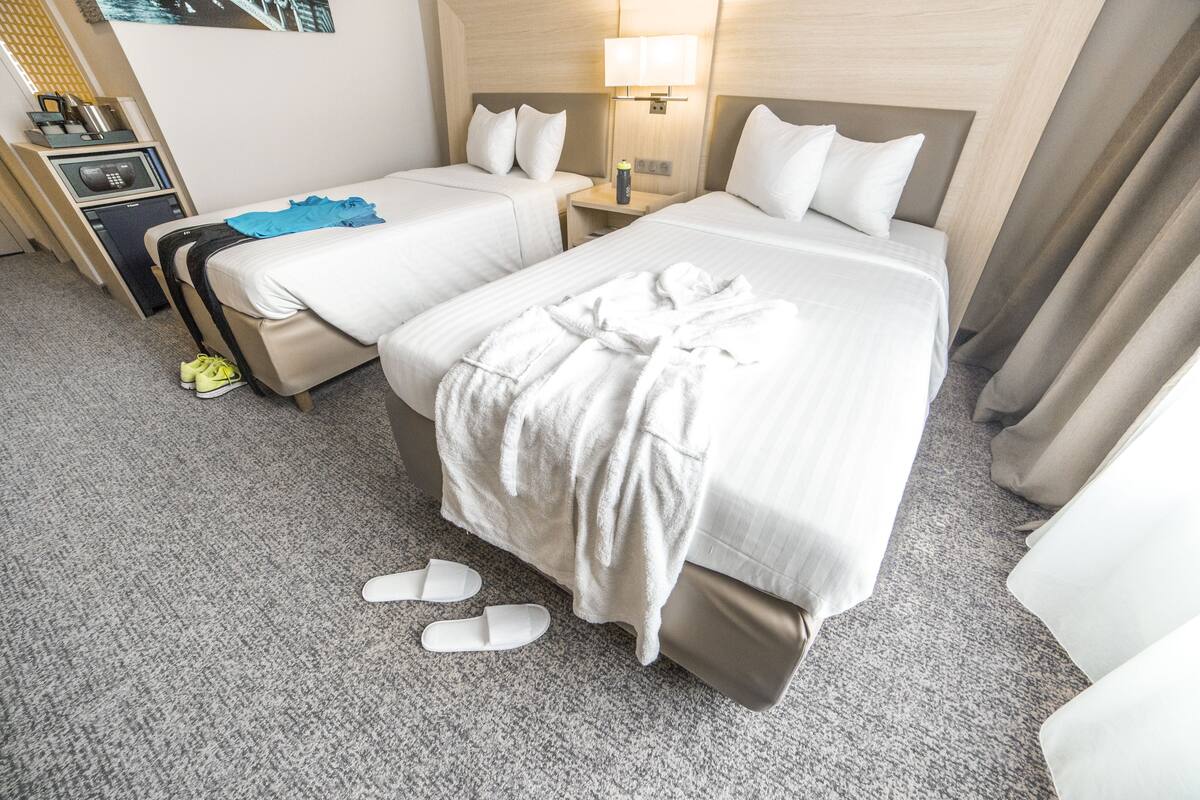 Een hotelkamer met twee bedden, een bureau, een lamp en een koffer.