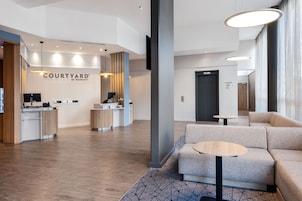 Un moderno vestíbulo de hotel con mostrador de recepción, zona de estar y un letrero de Courtyard by Marriott.