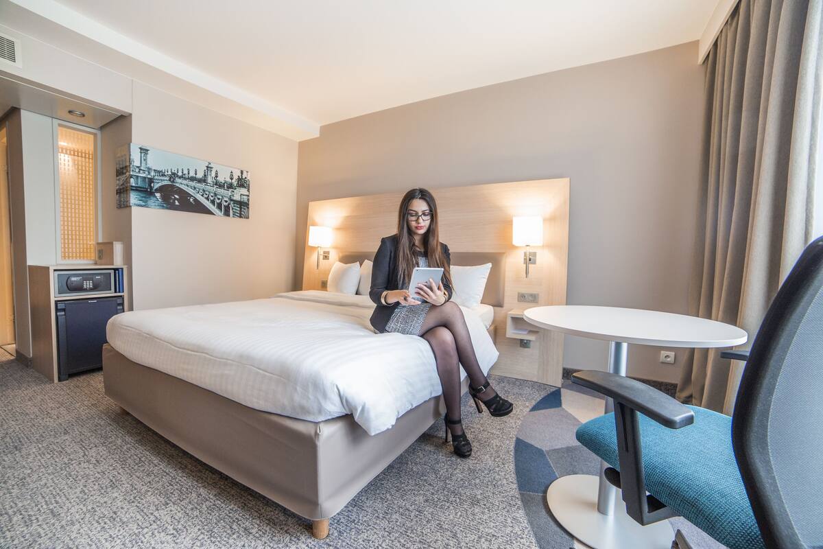 Een hotelkamer met een bed, een bureau, een stoel en een klein tafeltje.