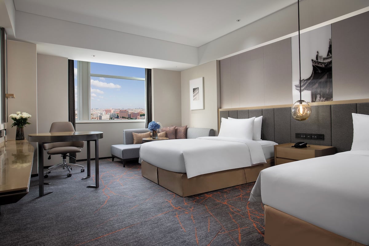 Una habitación de hotel moderna con una cama grande, un escritorio y vistas a la ciudad.