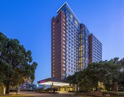 A high-rise hotel with a modern design, featuring a prominent entrance and a well-maintained surrounding area with trees.