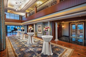 A spacious lobby with a high ceiling, chandeliers, and a grand staircase.