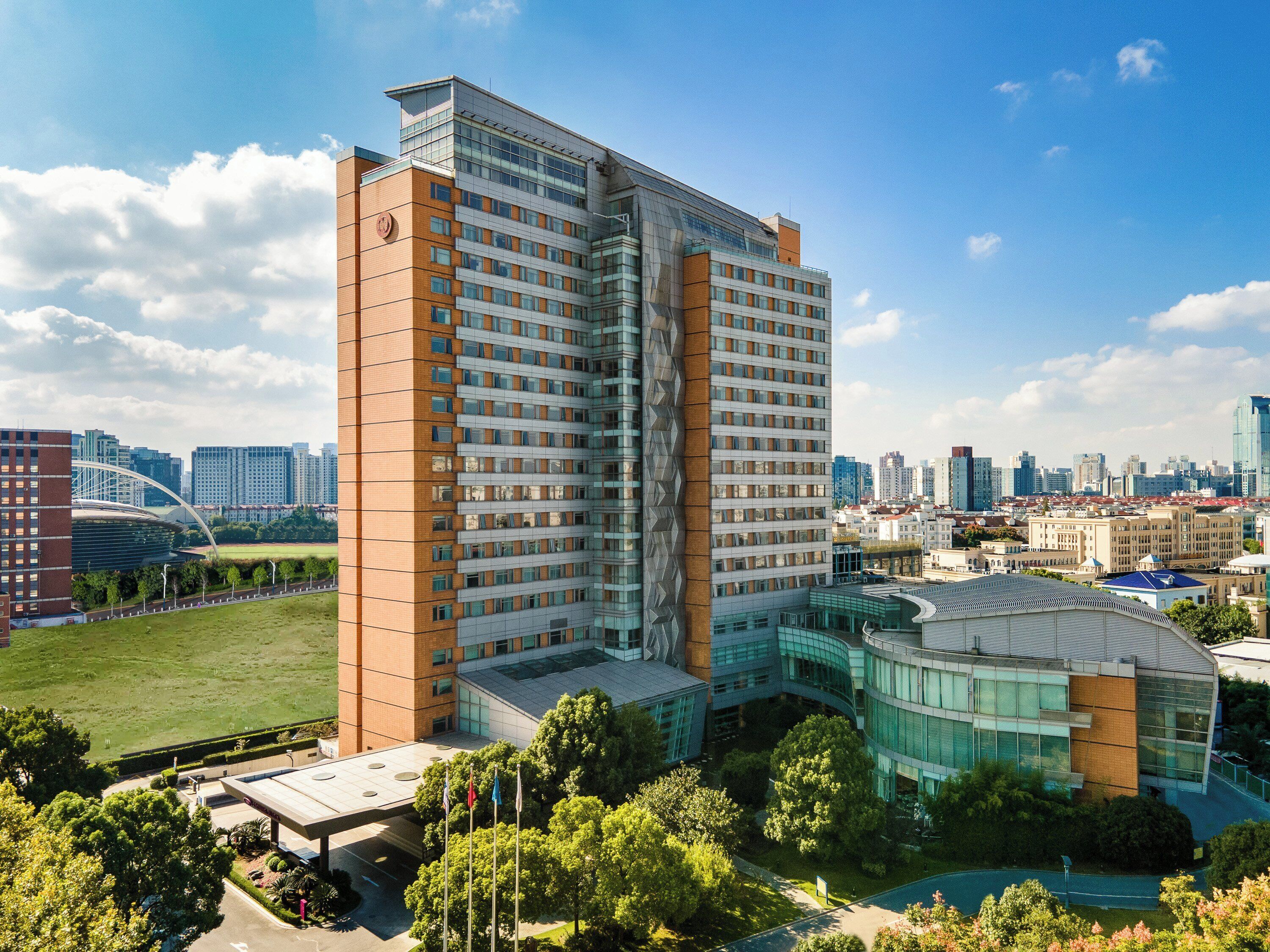 A high-rise hotel with a modern architectural design, featuring a prominent glass facade and a rooftop terrace.