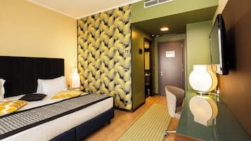 Una habitación de hotel con cama, espejo, televisor y pared con diseño.