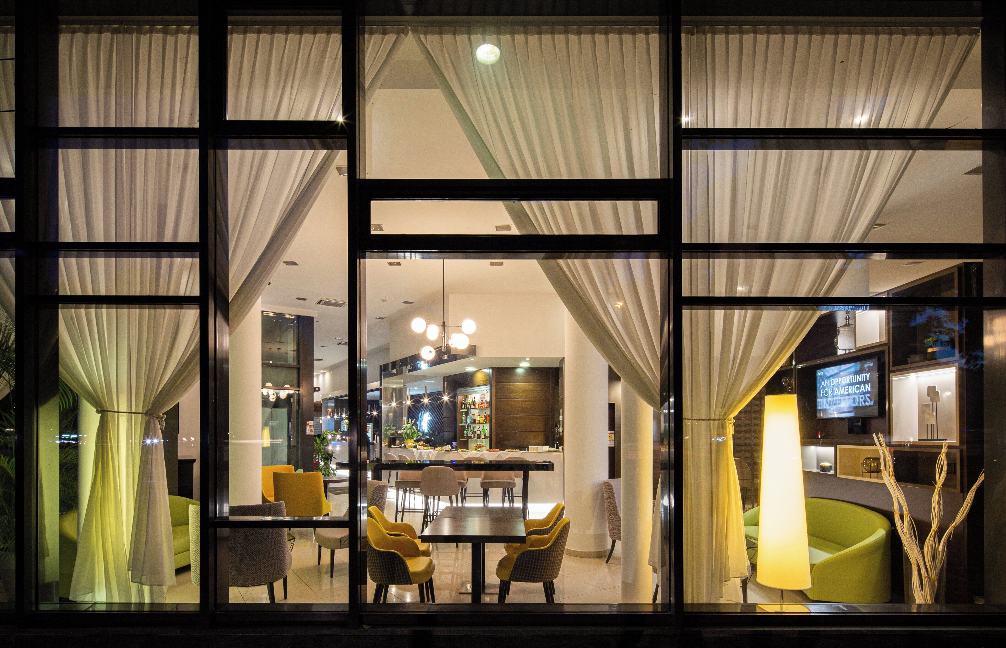 A hotel lobby with a bar area, seating, and a television screen.