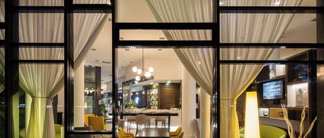 A hotel lobby with a bar area, seating, and a television screen.