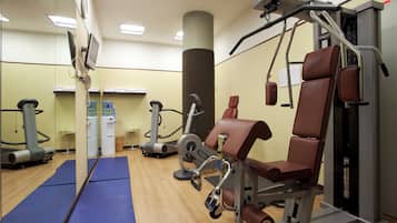 Een sportschool met trainingsapparatuur, een waterkraan en een spiegel.