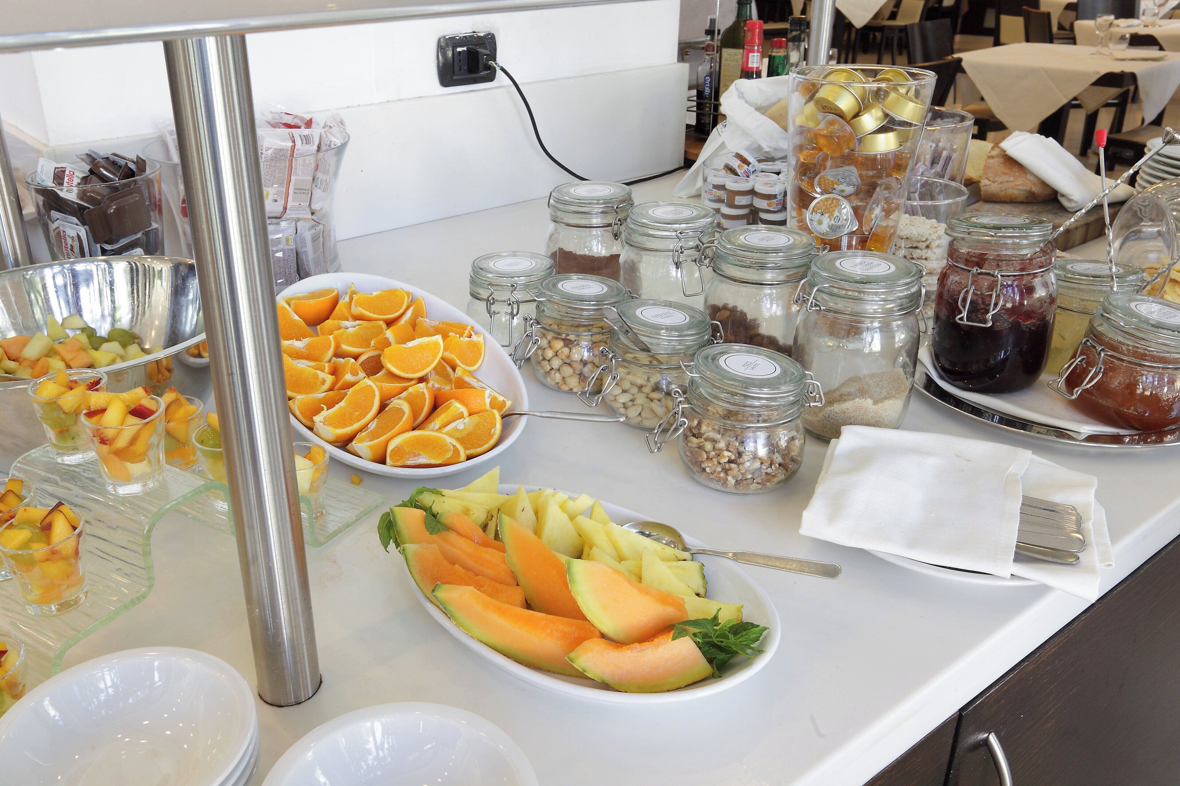 A buffet table with various food items including fruits, nuts, and condiments.