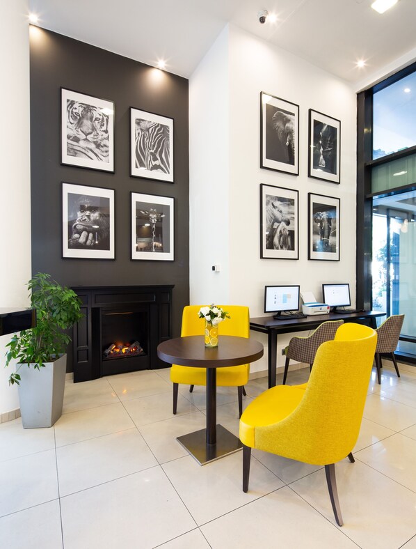Een modern interieur met een open haard, afbeeldingen van dieren in lijsten en gele stoelen.