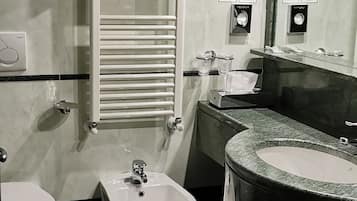 Un baño moderno con bidé, inodoro y un lavamanos amplio.
