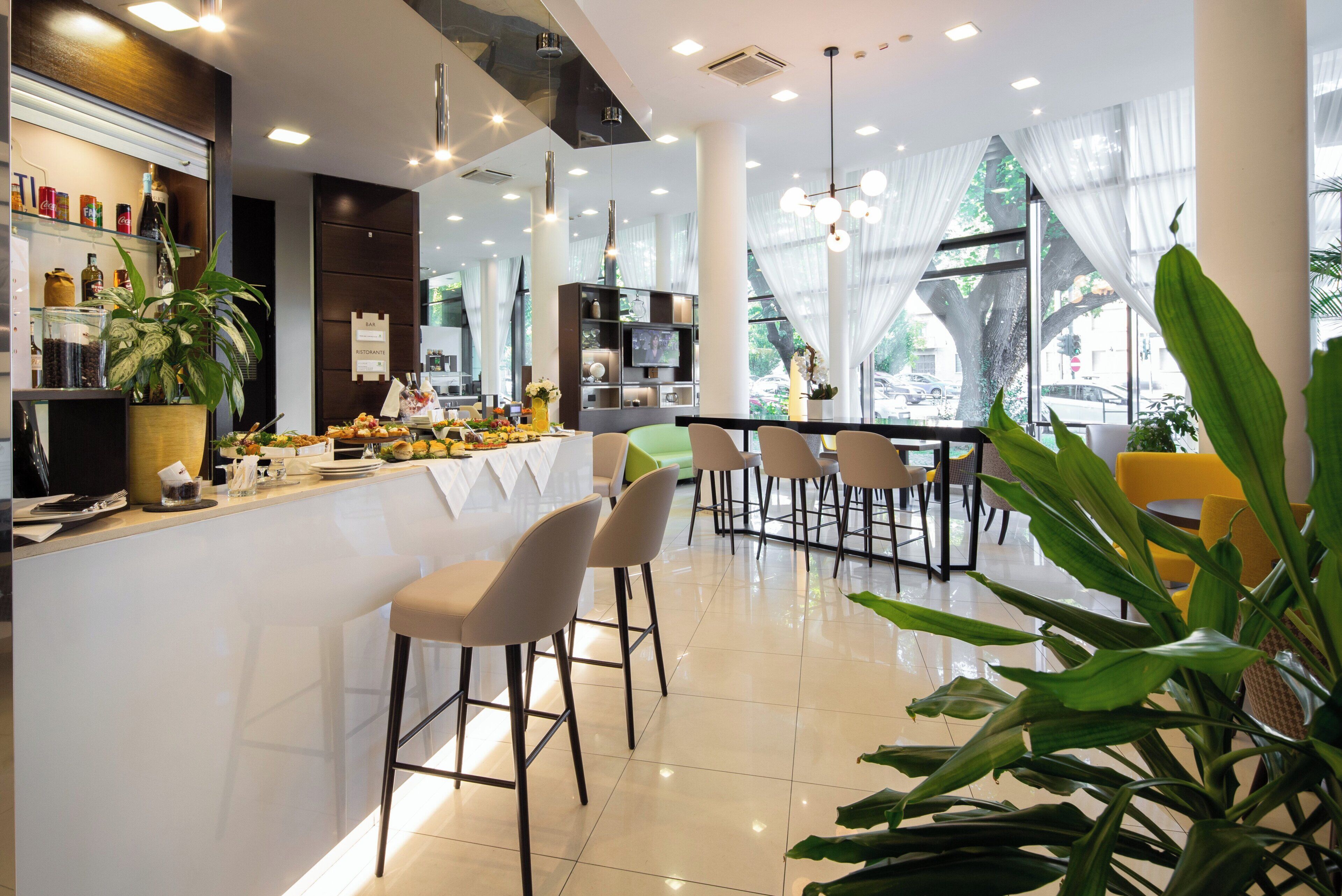 A modern bar area with a white countertop, bar stools, and a variety of food and drink items.