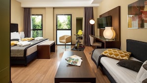 A hotel room with a bed, a sofa, a desk, a chair, a TV, and a window with curtains. - Holiday Inn Turin Corso Francia by IHG (Turin)