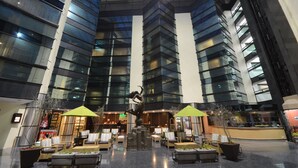 A modern hotel lobby with a central sculpture, seating areas, and a glass ceiling. - Hotel Misión Pachuca (Pachuca)