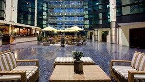 A spacious lobby with a central seating area, multiple floors of glass windows, and a restaurant on the left. - Hotel Misión Pachuca (Pachuca)