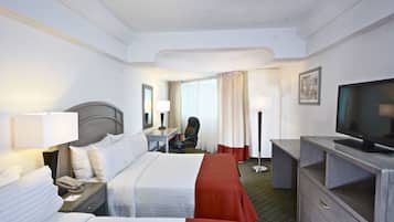 A hotel room with two beds, a desk, a chair, a television, and a wardrobe.