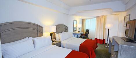A hotel room with two beds, a desk, a chair, a television, and a dresser.