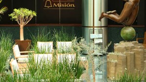 A hotel lobby with a bronze statue, a sign reading "HOTEL Misión", and indoor plants. - Hotel Misión Pachuca (Pachuca)