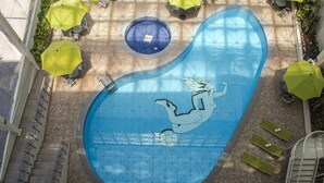An aerial view of a swimming pool with a mermaid mural, surrounded by sun loungers and umbrellas. - Hotel Misión Pachuca (Pachuca)