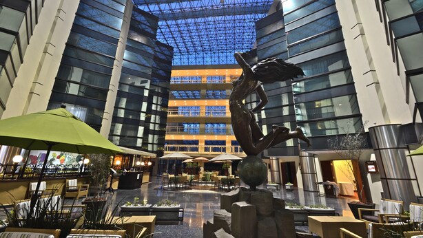 A spacious indoor area with a high ceiling, large windows, and a central sculpture. - Hotel Misión Pachuca (Pachuca)