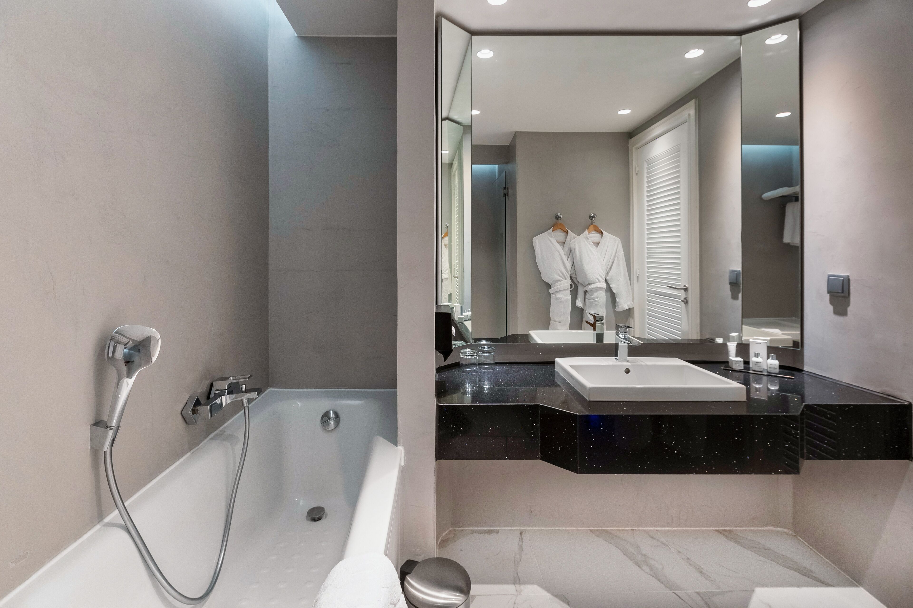 Un baño moderno con bañera, lavamanos y un espejo grande.