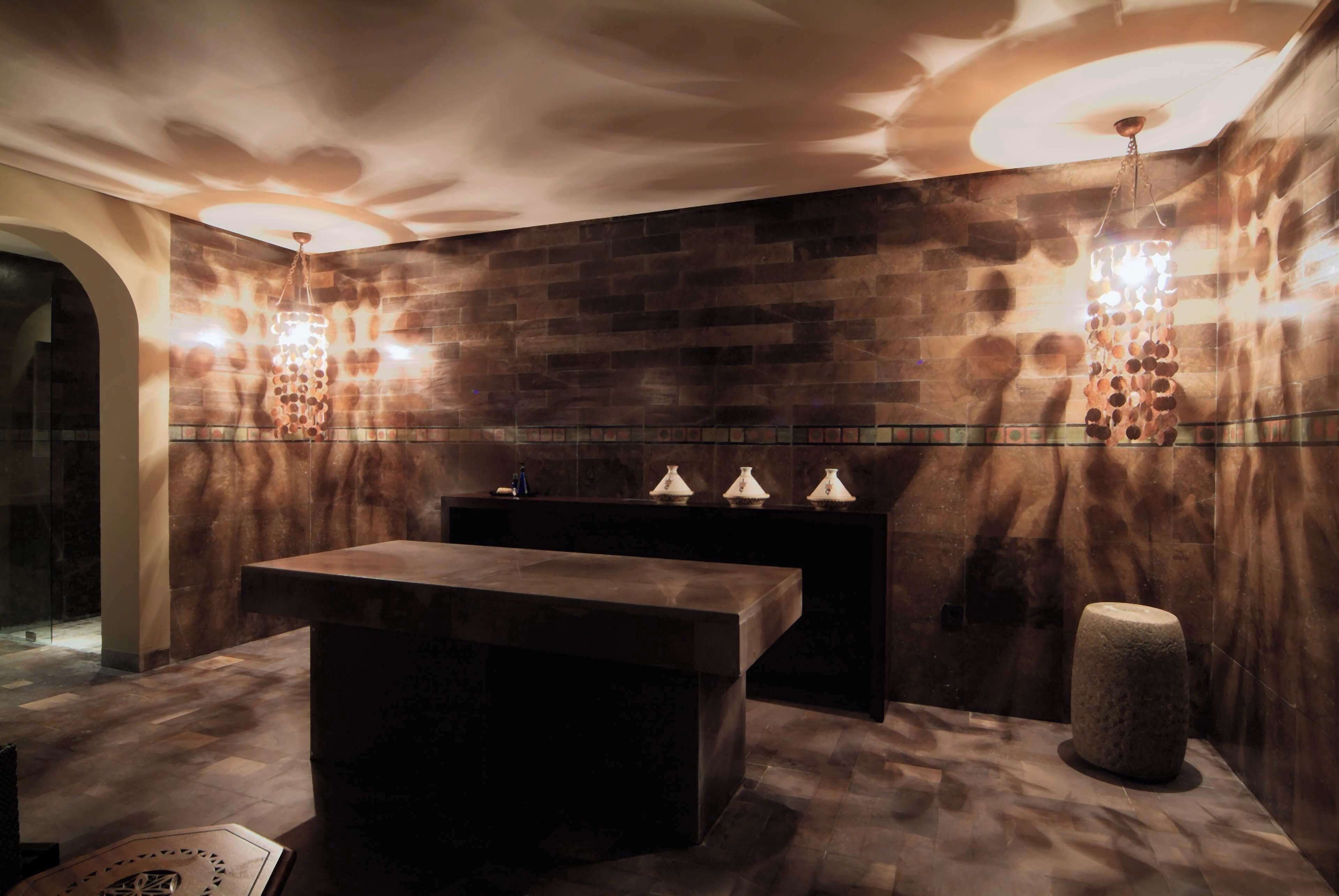 A modern bathroom with a large mirror, a bench, and a stone accent piece.