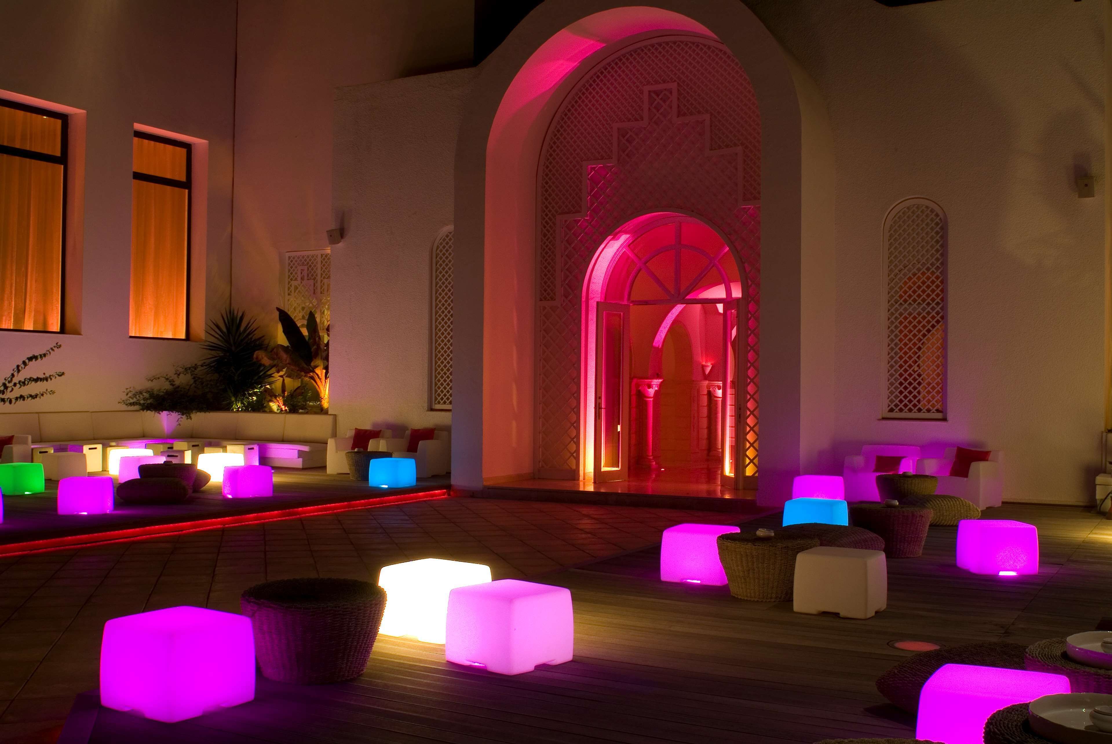 Un área de estar moderna con asientos iluminados y un llamativo arco.