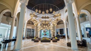 A spacious lobby with a grand chandelier, marble columns, and a piano. - Radisson Blu Athénée Palace Resort & Thalasso, Djerba (Mezraia)