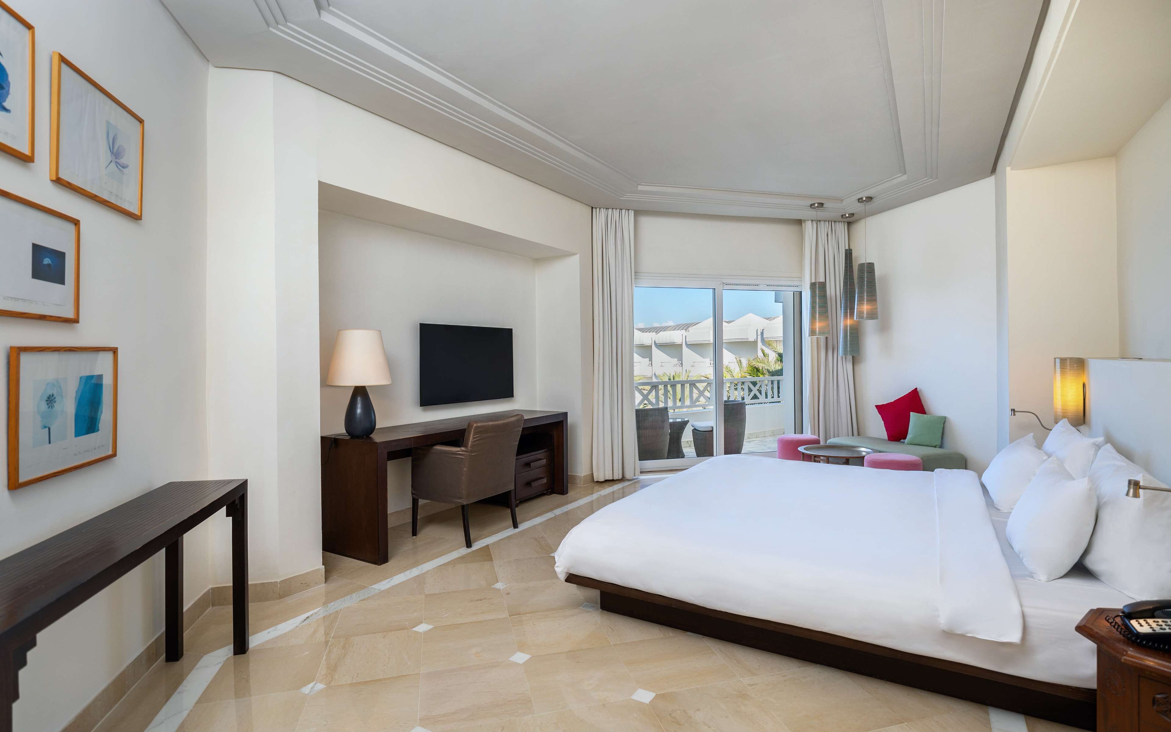 Une chambre d’hôtel comprenant un lit, un bureau, une télévision et un balcon avec des meubles d’extérieur.