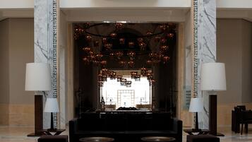 A lobby with a grand arched entrance, a central seating area, and a decorative chandelier.