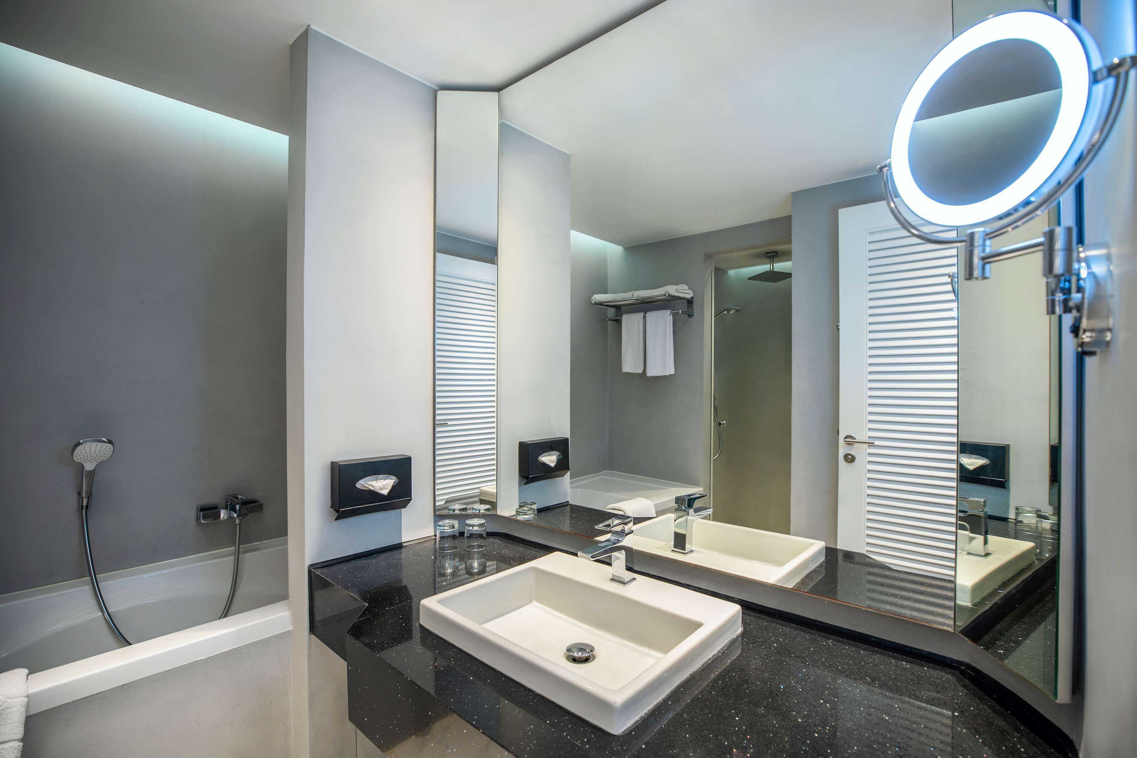 Un baño moderno con un espejo grande, dos lavamanos, una ducha y un mueble de tocador con un perchero.