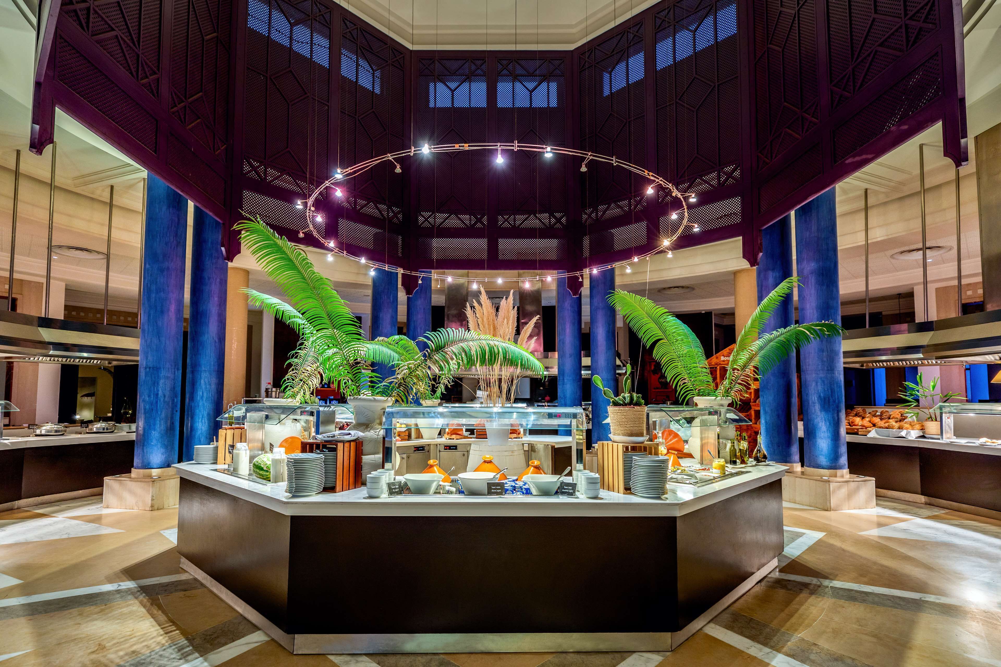 A spacious lobby with a central counter, large columns, and a decorative ceiling.