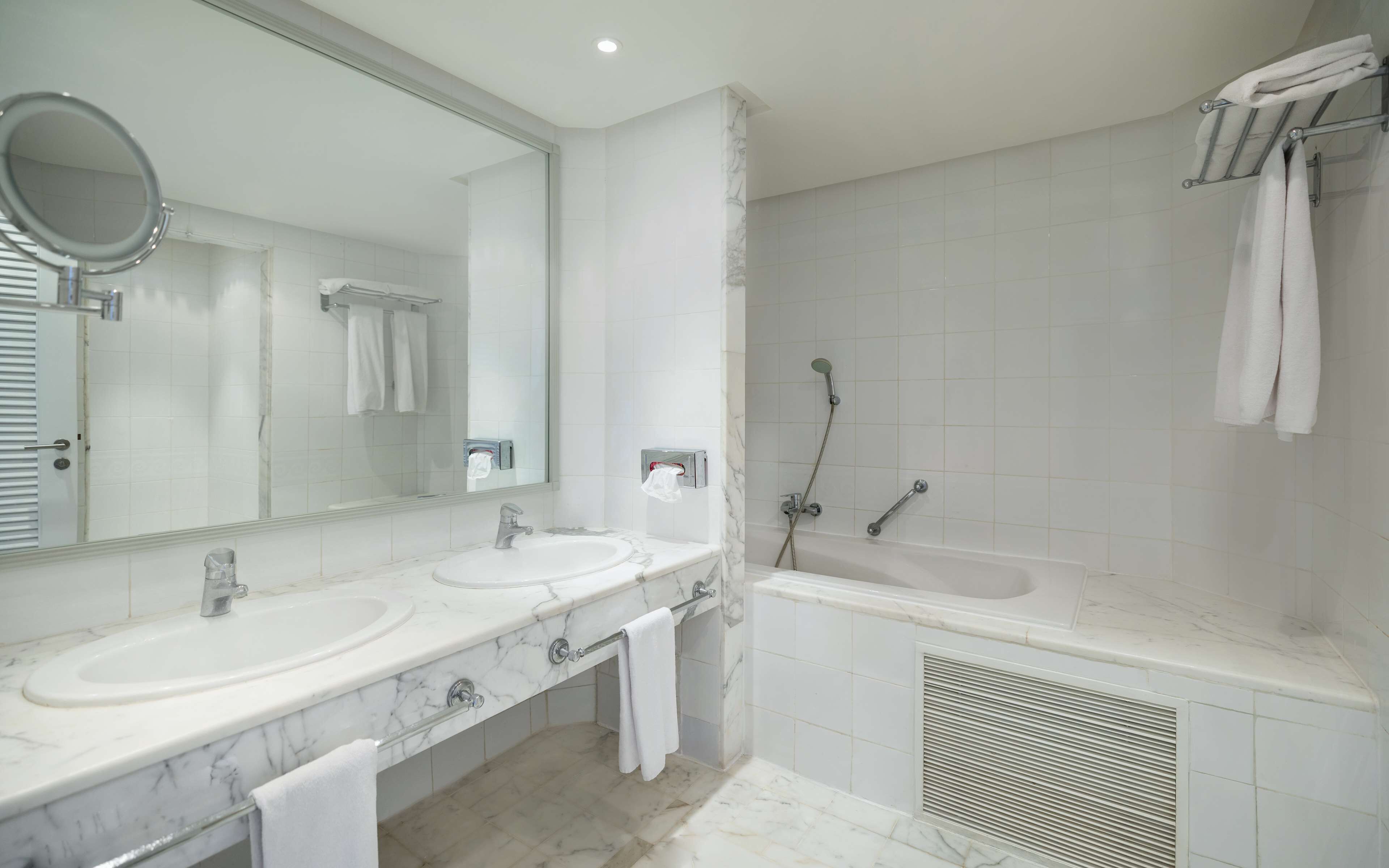 A bathroom with two sinks, a large mirror, a shower, and a bathtub.