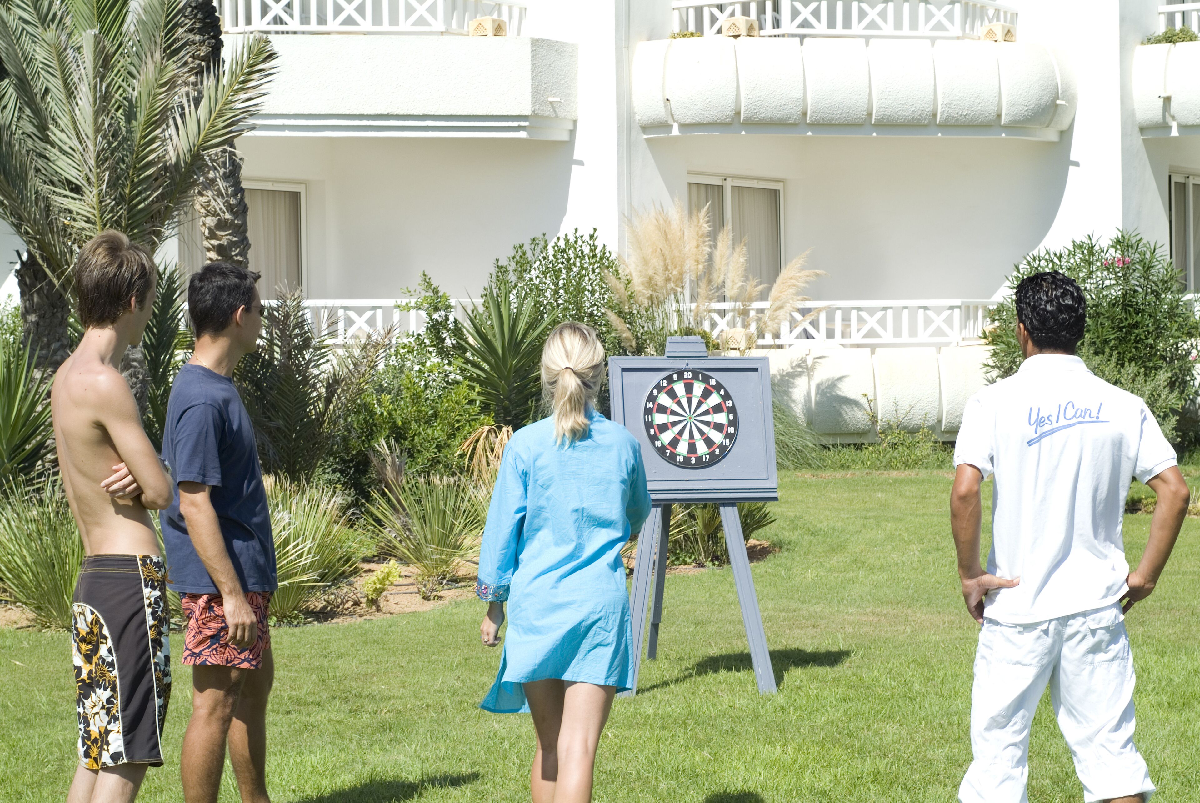 A group of people standing outdoors near a dartboard.