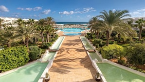A resort pool area with multiple swimming pools, palm trees, and a clear view of the ocean. - Radisson Blu Athénée Palace Resort & Thalasso, Djerba (Mezraia)