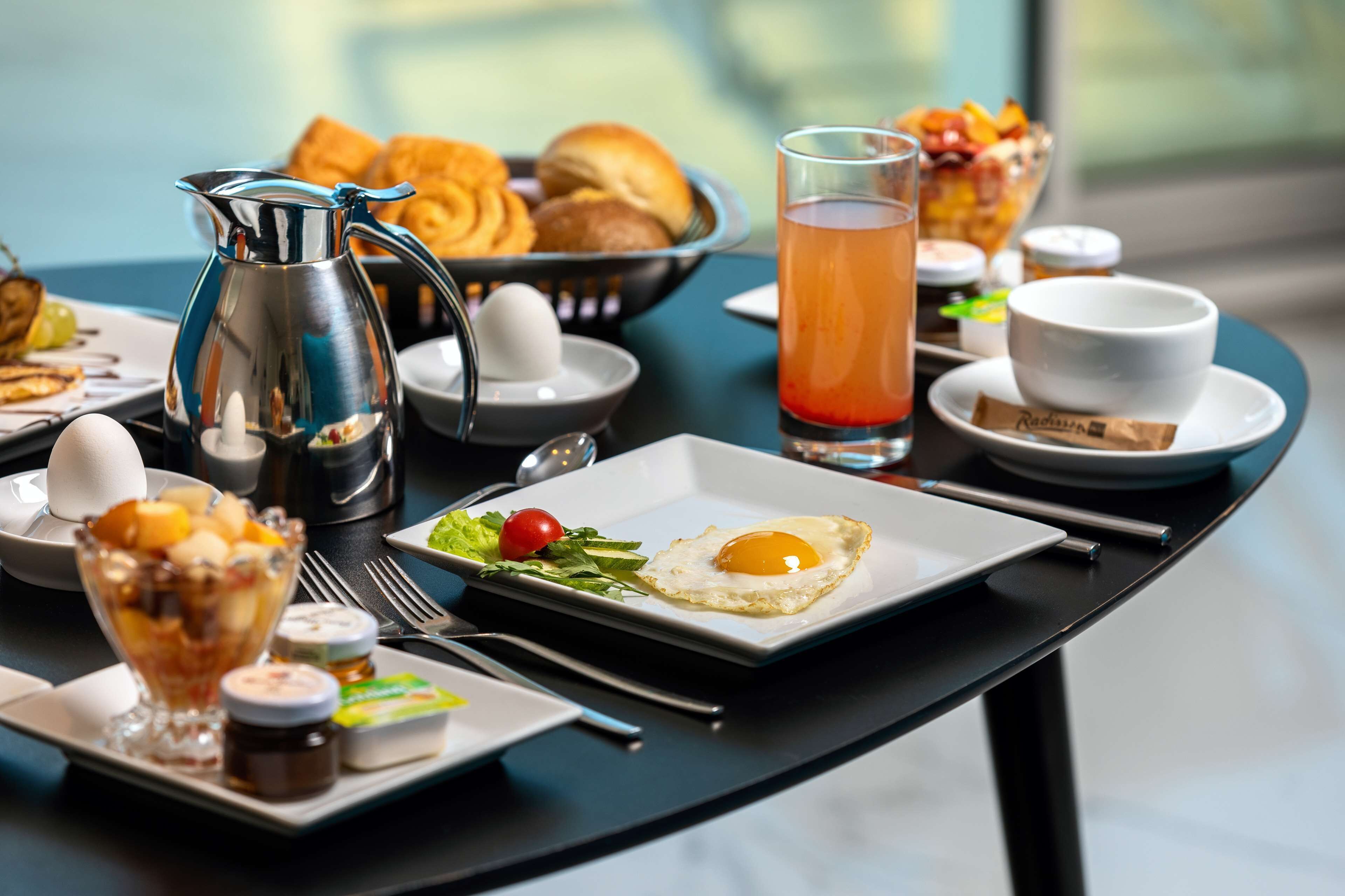 Une table mise pour le petit-déjeuner avec une carafe, des toasts, des fruits, un verre de jus et une assiette avec un œuf.