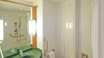 A bathroom with a green sink, a mirror, a shower, and a toilet.