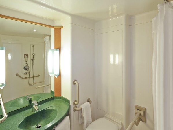 A bathroom with a green sink, a mirror, a shower, and a toilet.