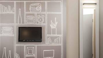 A modern room with a flat-screen TV mounted on a chalkboard wall, a mirror, and a door with a light above it.