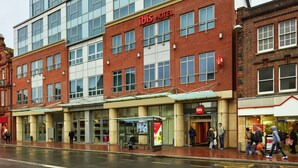 Een modern hotel met een glazen gevel en een fundering van rode baksteen.