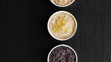 Tres tazones con distintos alimentos sobre una superficie oscura.