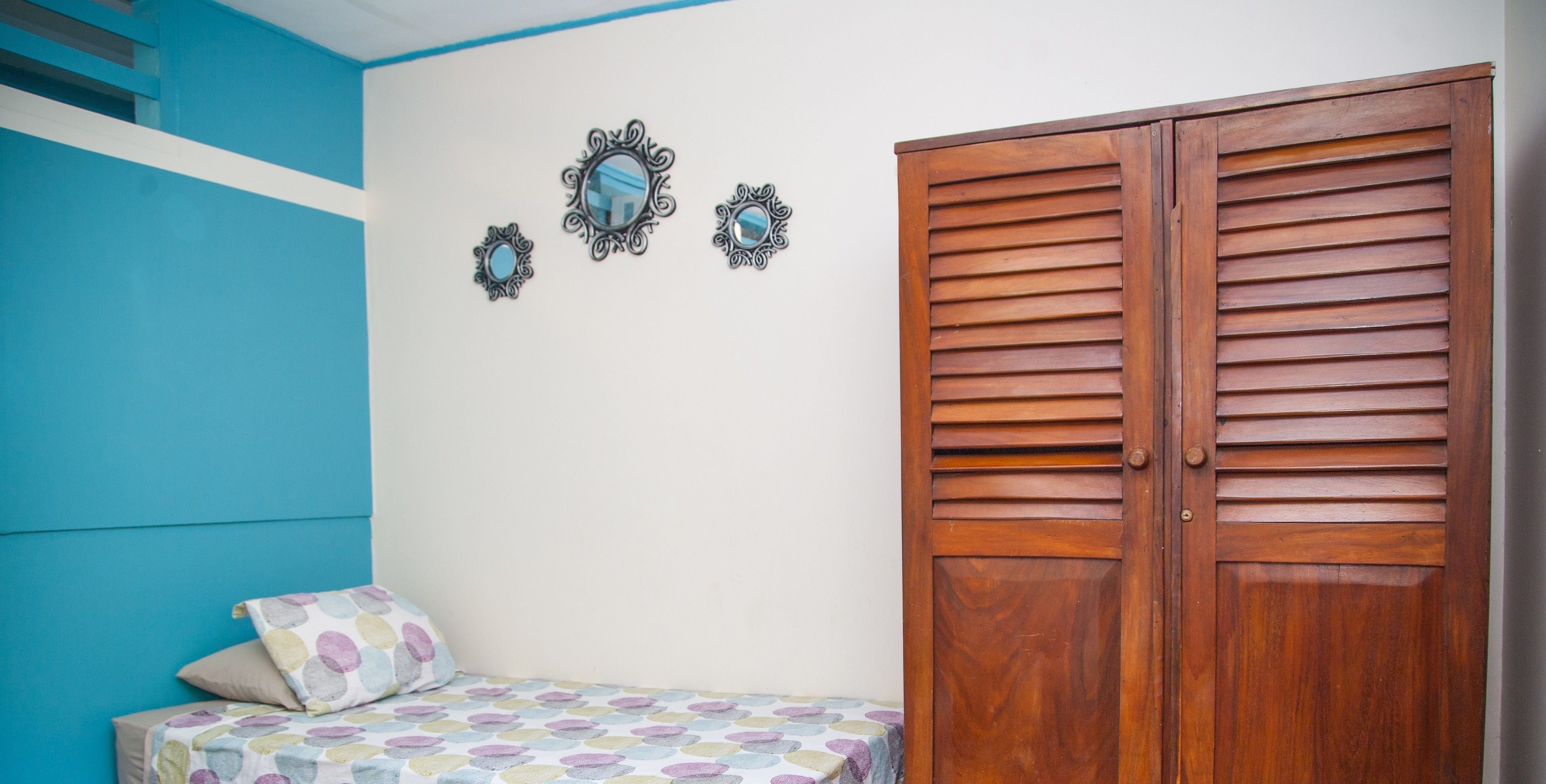 Ein Schlafzimmer mit einem Bett, einem Kleiderschrank und dekorativen Spiegeln an der Wand.