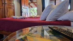Ein Hotelzimmer mit einem Bett, Kissen, einer Fernbedienung und einem Glastisch.