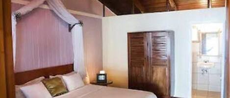 Quarto com cama, mesa de cabeceira e porta de madeira.