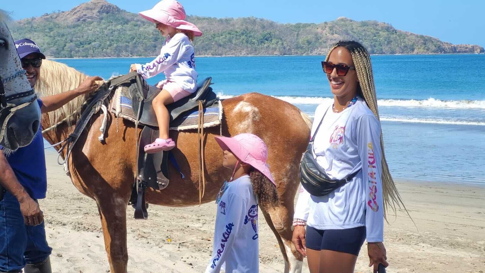 A beach scene with a horse and people.