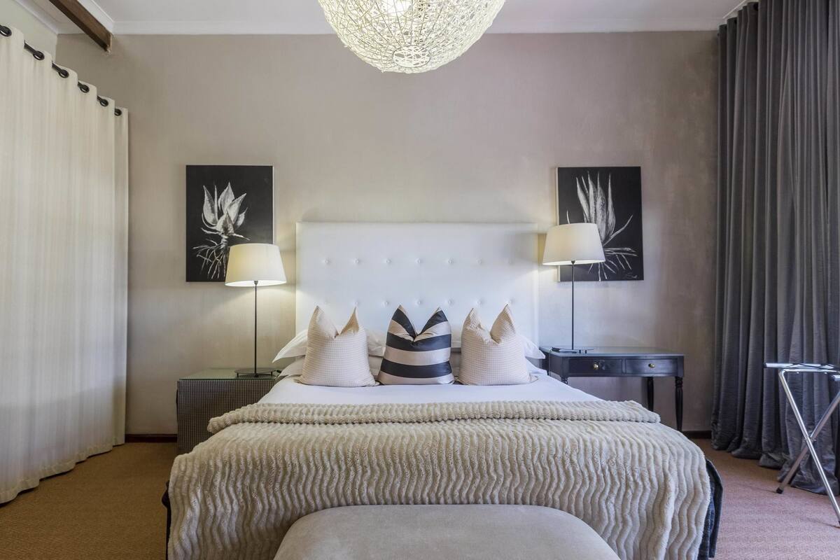 A hotel room with a large bed, two bedside tables, a standing lamp, and artwork on the walls.