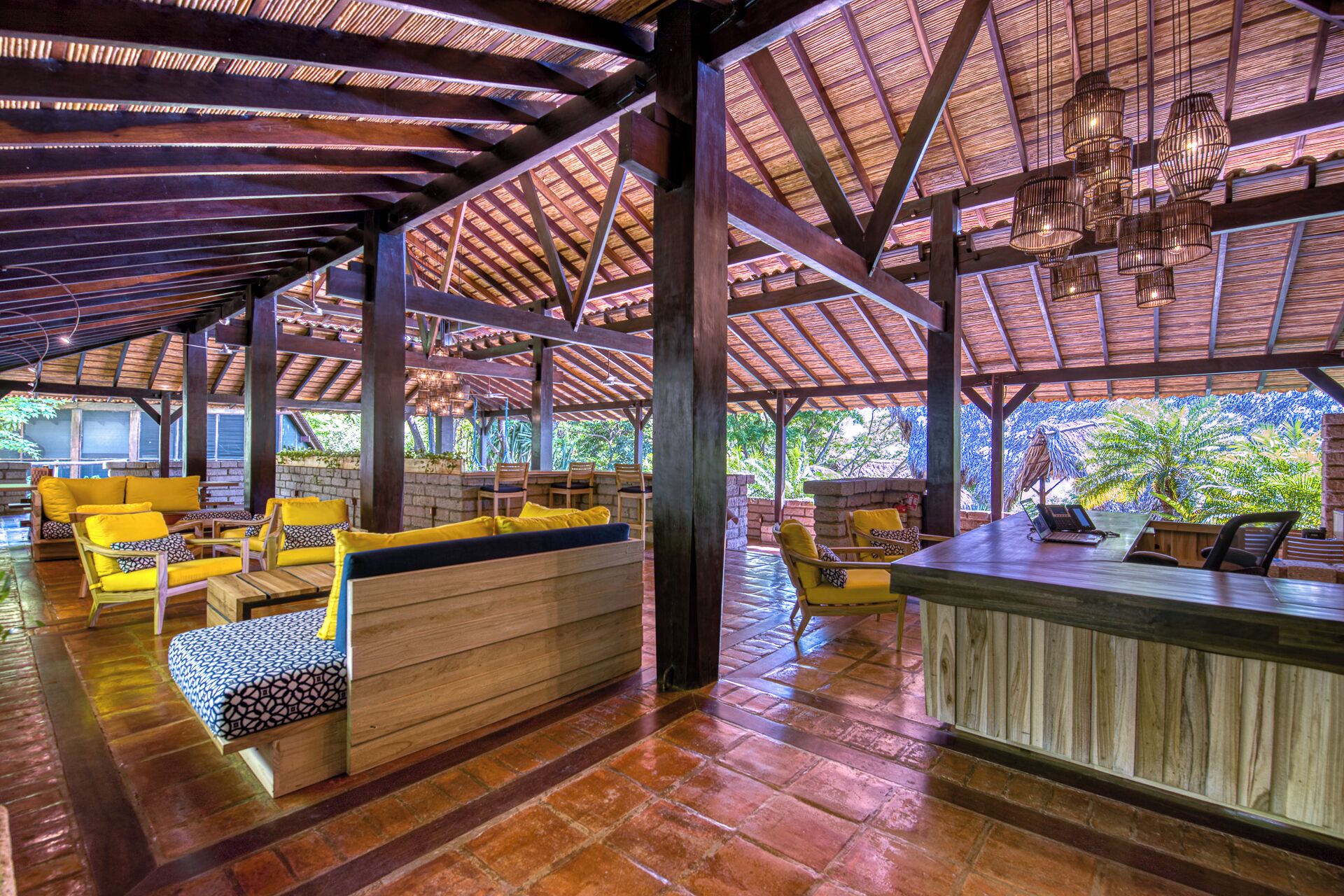 A covered outdoor seating area with wooden furniture and a bar.