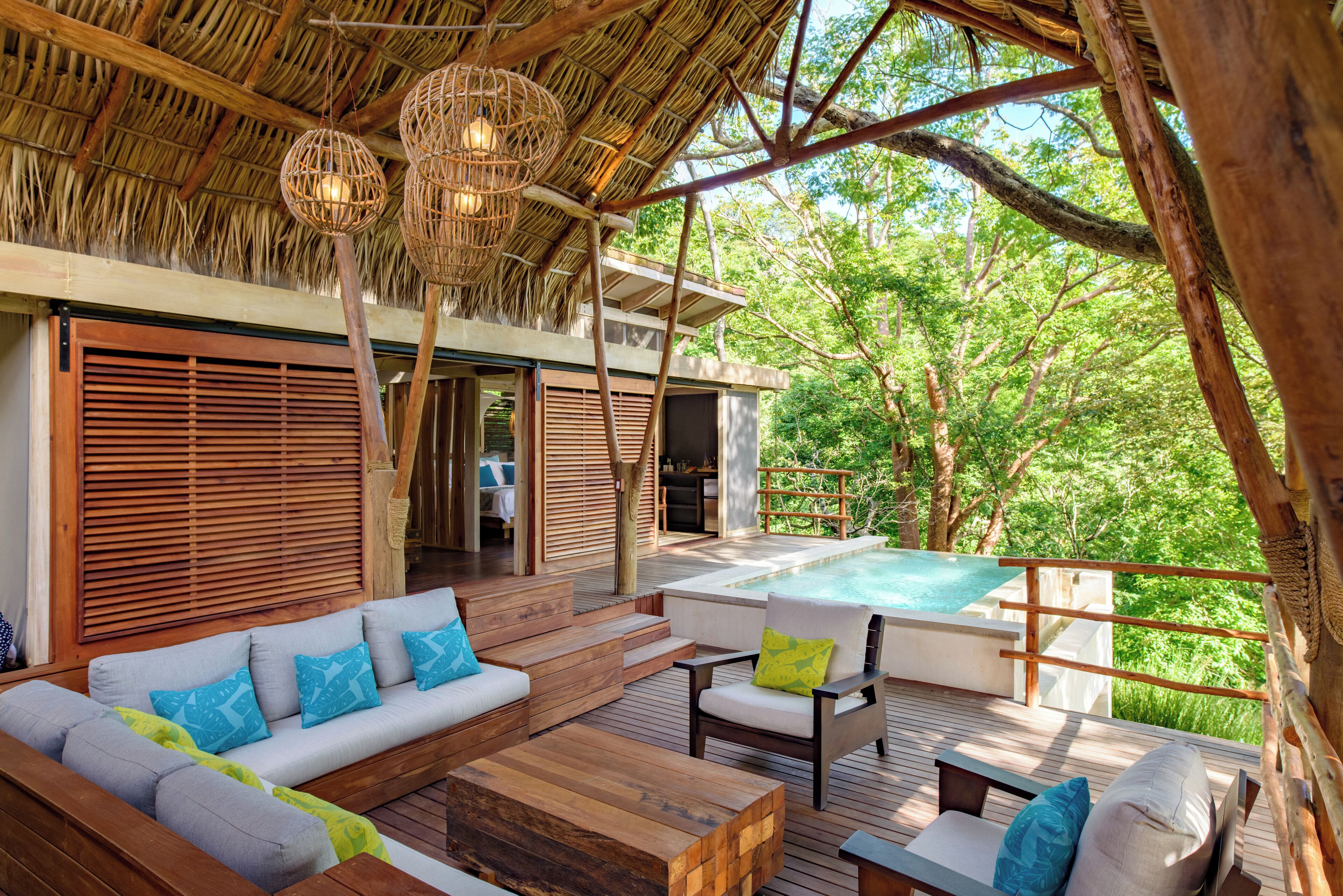 A wooden deck with a sofa, chairs, and a hot tub.