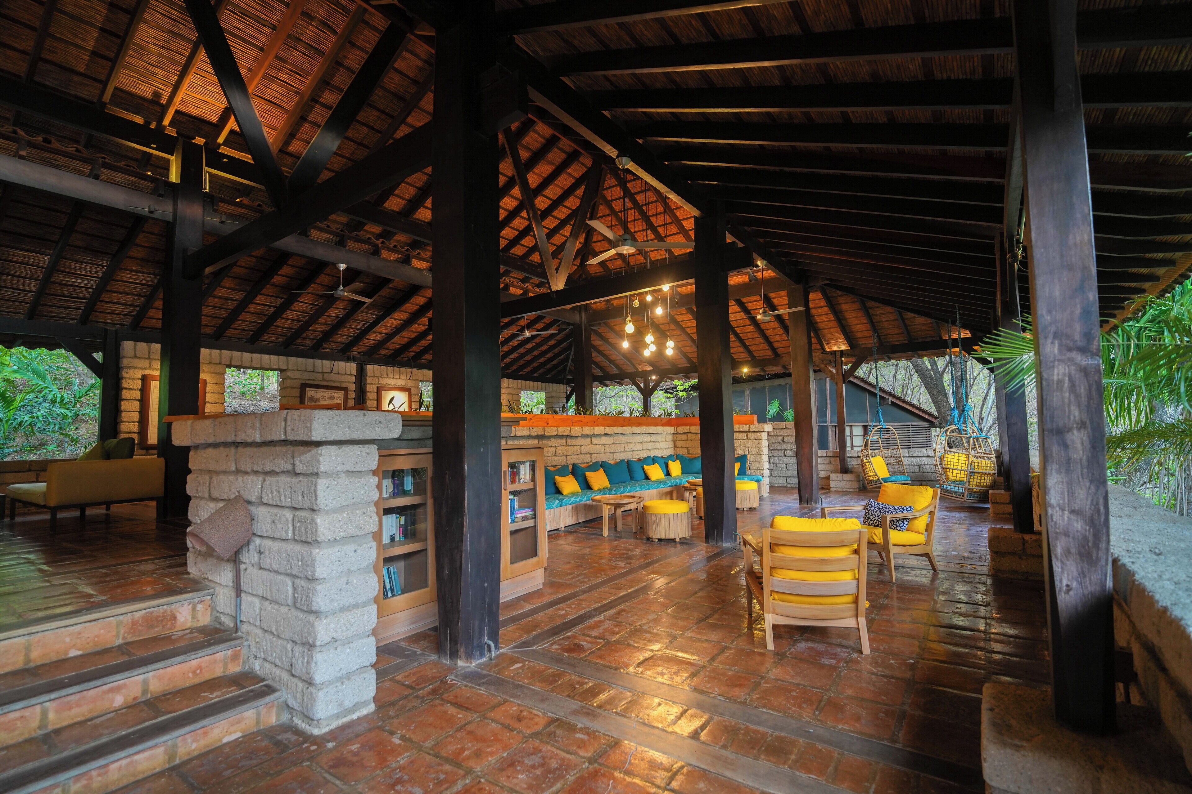 Un espacio al aire libre techado con paredes de ladrillo, muebles de madera y luces colgantes.